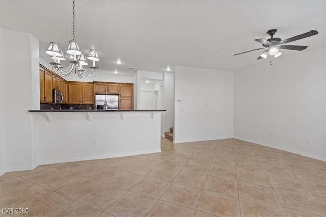 kitchen with light tile patterned floors, hanging light fixtures, stainless steel appliances, ceiling fan with notable chandelier, and kitchen peninsula