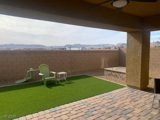 view of yard with ceiling fan, a mountain view, and a patio area