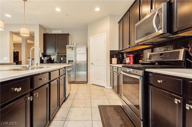 kitchen featuring stainless steel appliances, sink, dark brown cabinetry, and decorative light fixtures