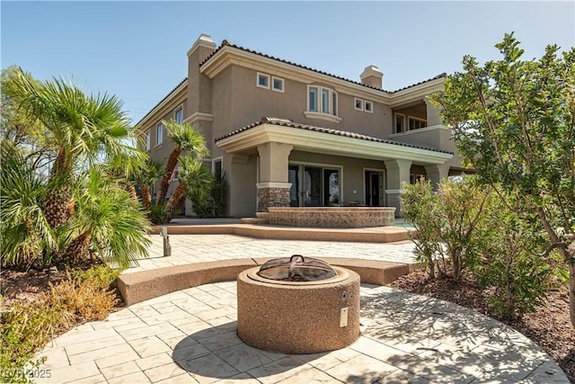 rear view of property with a patio and an outdoor fire pit