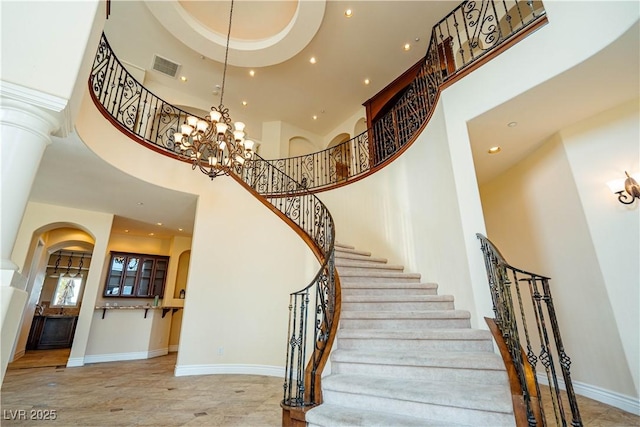 stairs with a towering ceiling and a notable chandelier