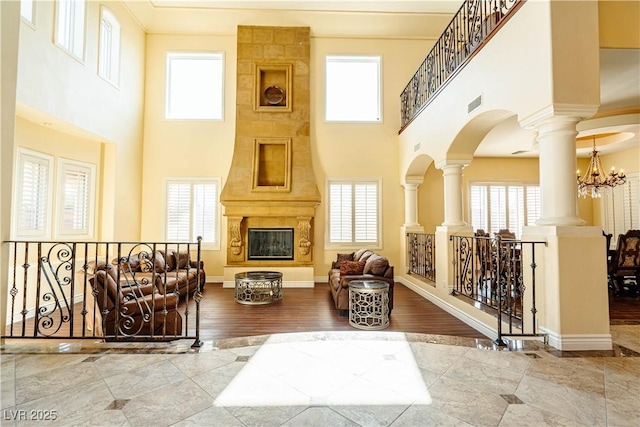 interior space with hardwood / wood-style floors, a large fireplace, a healthy amount of sunlight, and ornate columns