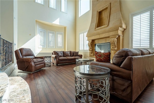 living room with dark wood-type flooring, a premium fireplace, and a healthy amount of sunlight