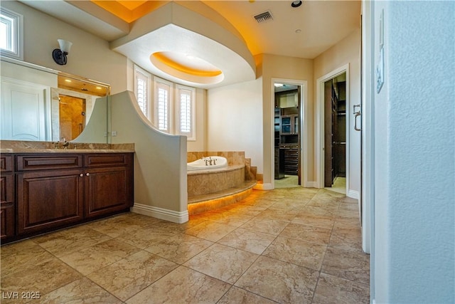 bathroom with vanity and tiled bath