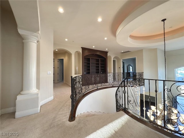 hall with light colored carpet and ornate columns