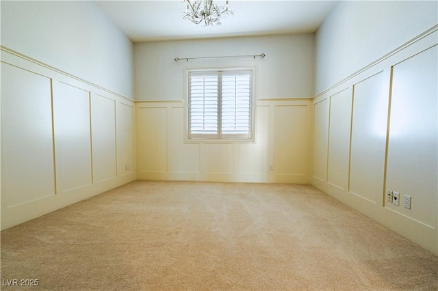 spare room featuring an inviting chandelier and light colored carpet