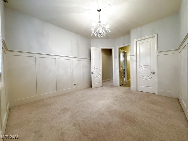 unfurnished bedroom featuring a notable chandelier, light colored carpet, and multiple closets