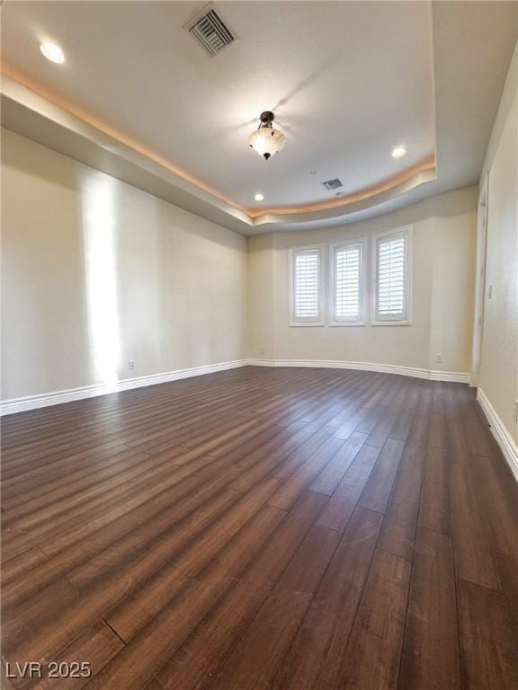 unfurnished room featuring dark hardwood / wood-style flooring and a raised ceiling