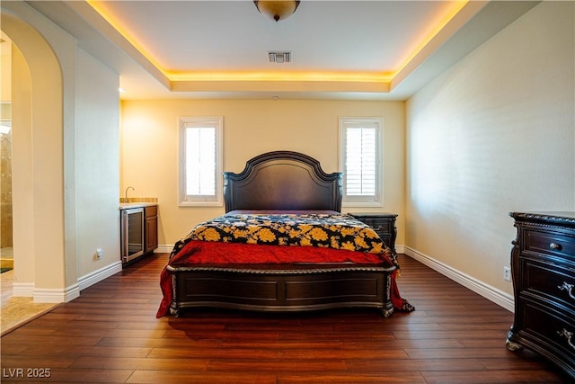 bedroom featuring dark wood-type flooring, a tray ceiling, and wine cooler