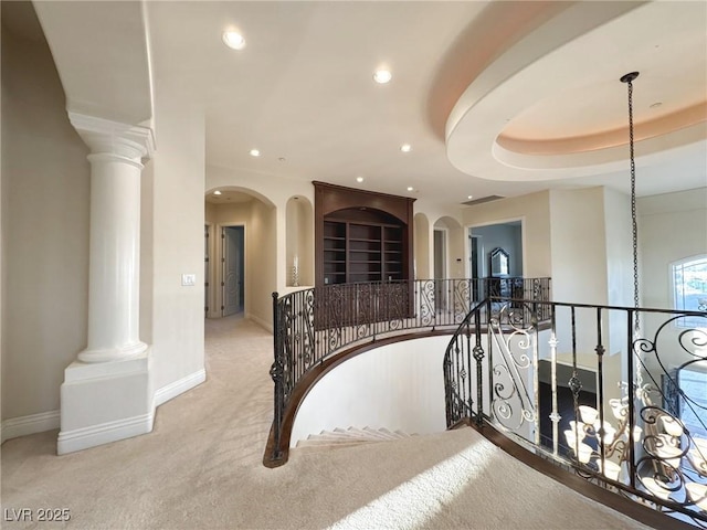 hallway featuring light colored carpet and decorative columns