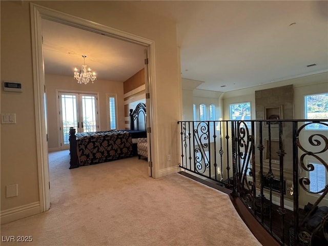 hallway with an inviting chandelier and carpet floors