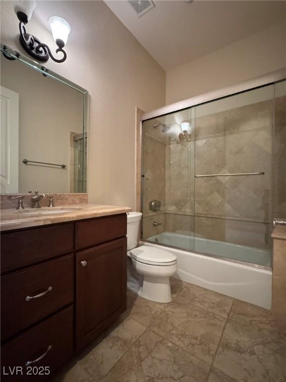 full bathroom with enclosed tub / shower combo, vanity, and toilet