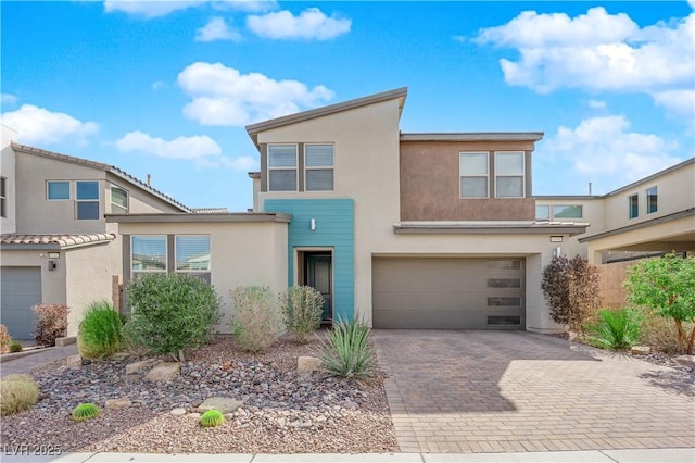 contemporary house with decorative driveway, an attached garage, and stucco siding