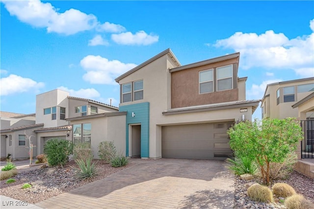 view of front of home featuring decorative driveway, an attached garage, and stucco siding