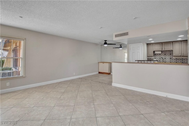 unfurnished living room with ceiling fan, a textured ceiling, and light tile patterned floors