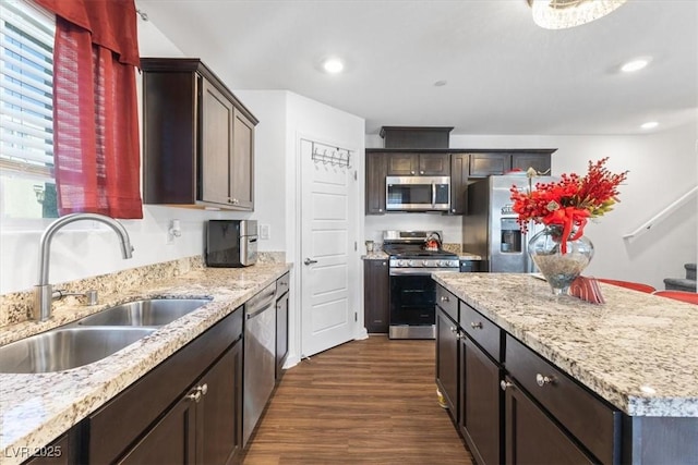 kitchen with light stone counters, sink, dark hardwood / wood-style floors, and appliances with stainless steel finishes