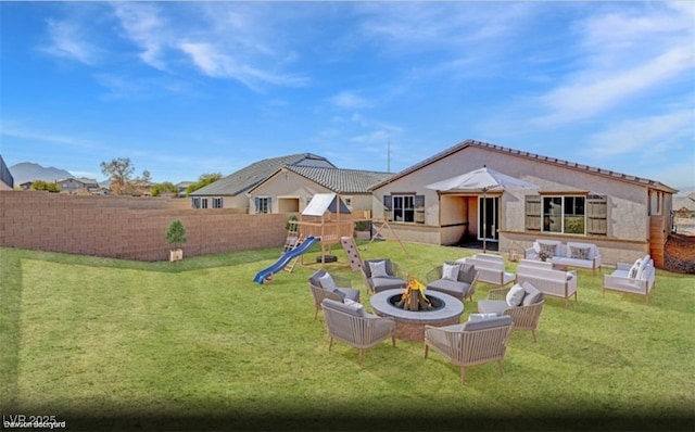 back of property with a playground, a yard, and an outdoor living space with a fire pit