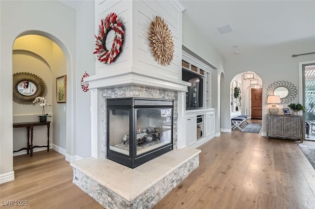 living room with built in shelves and light hardwood / wood-style flooring