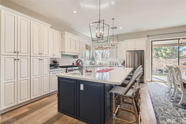 kitchen featuring white cabinetry, decorative light fixtures, a breakfast bar, and an island with sink