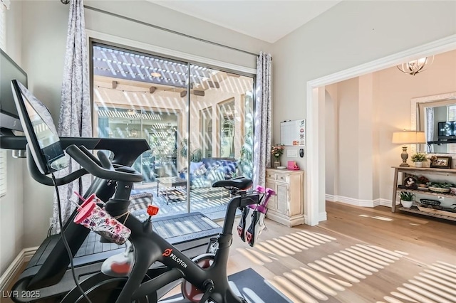 workout area featuring a notable chandelier and light hardwood / wood-style floors