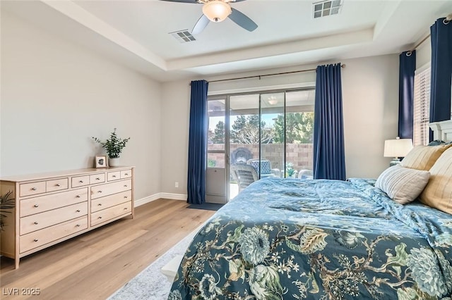 bedroom with a raised ceiling, ceiling fan, access to exterior, and light wood-type flooring