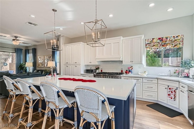 kitchen featuring pendant lighting, an island with sink, and white cabinets