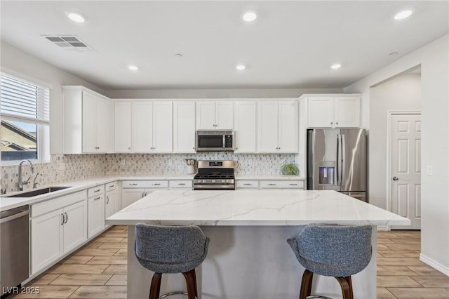 kitchen featuring stainless steel appliances, sink, a kitchen island, and white cabinets