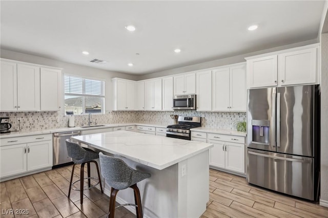 kitchen featuring sink, stainless steel appliances, white cabinets, and a kitchen island