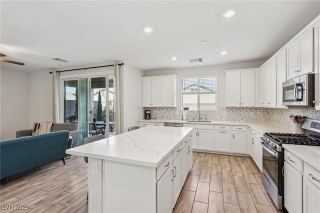 kitchen featuring sink, white cabinetry, a center island, stainless steel appliances, and backsplash