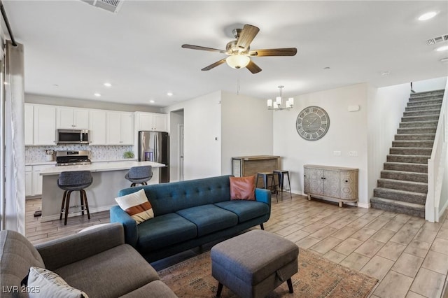 living room featuring ceiling fan with notable chandelier