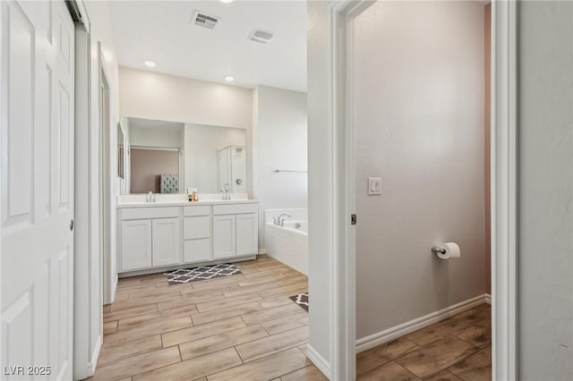 bathroom with vanity and tiled bath