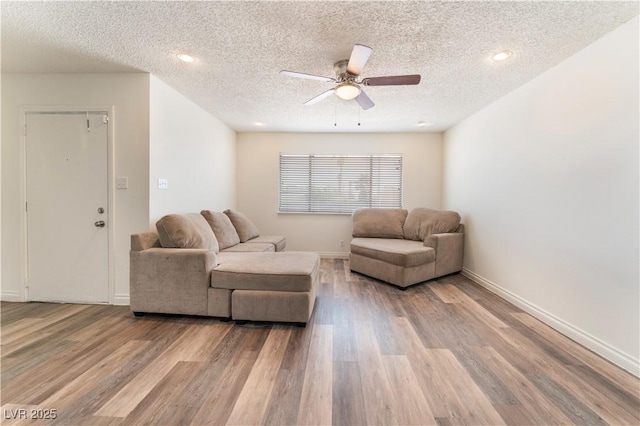 living room with a textured ceiling, ceiling fan, and light wood-type flooring