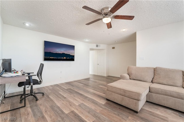 home office featuring wood-type flooring, ceiling fan, and a textured ceiling