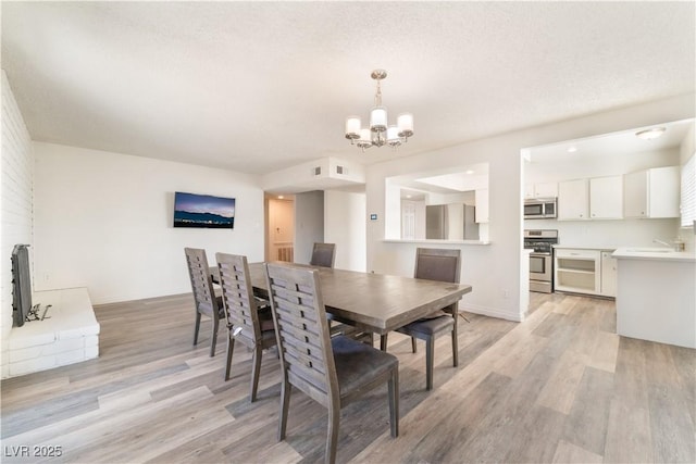 dining room with a notable chandelier, a textured ceiling, and light wood-type flooring