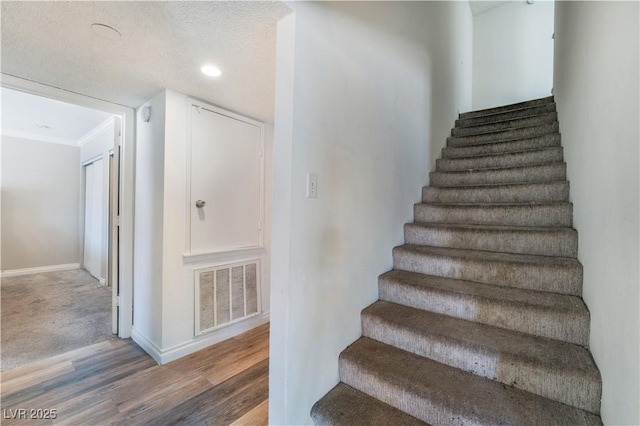 staircase featuring wood-type flooring and a textured ceiling