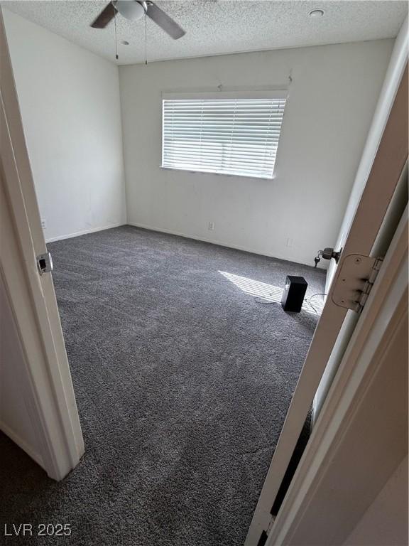 interior space with ceiling fan, a textured ceiling, and dark colored carpet