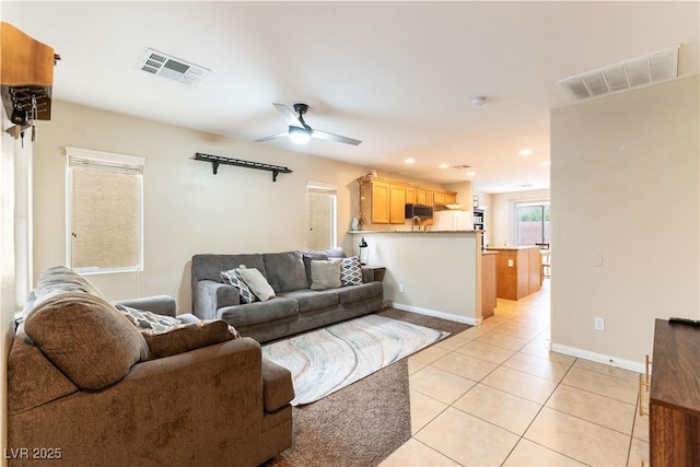 living area with baseboards, light tile patterned flooring, visible vents, and a ceiling fan