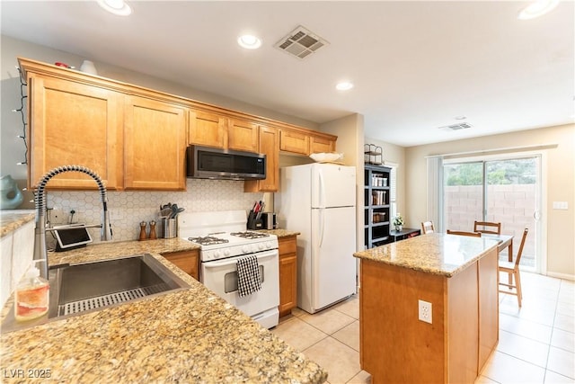 kitchen featuring white appliances, visible vents, a sink, light stone countertops, and backsplash