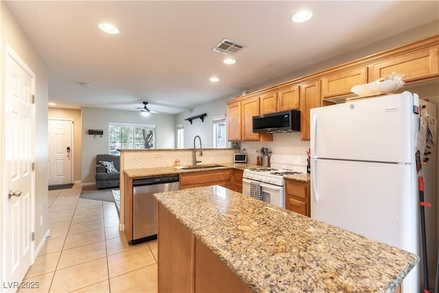 kitchen featuring light tile patterned flooring, a peninsula, white appliances, a sink, and visible vents