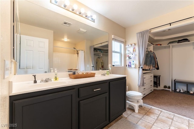 full bathroom featuring toilet, a sink, visible vents, a spacious closet, and double vanity