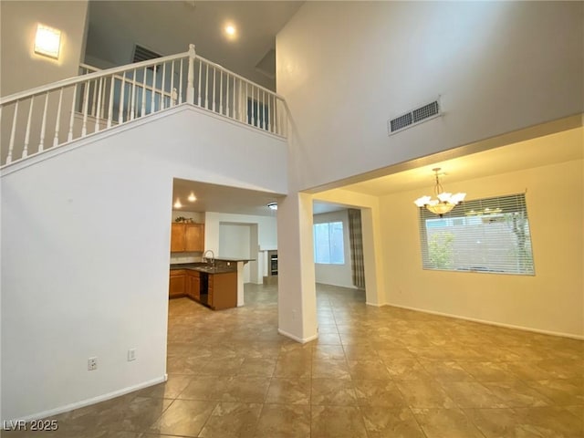 unfurnished living room featuring light tile patterned floors, sink, and a notable chandelier