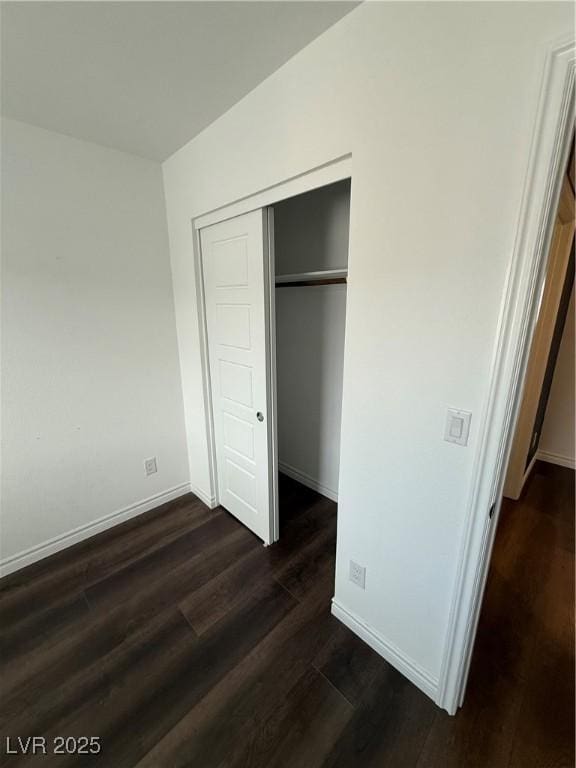 unfurnished bedroom with dark hardwood / wood-style flooring and a closet