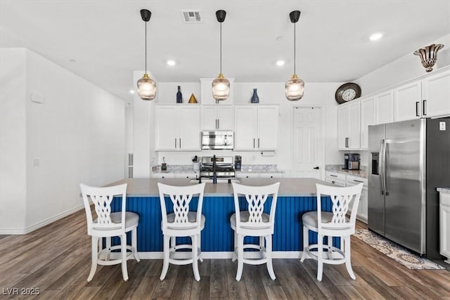 kitchen with stainless steel appliances, a kitchen island with sink, and white cabinets