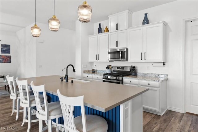 kitchen with sink, white cabinetry, appliances with stainless steel finishes, a kitchen breakfast bar, and an island with sink