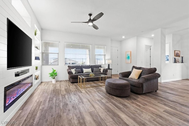 living room featuring ceiling fan, a fireplace, and light hardwood / wood-style floors