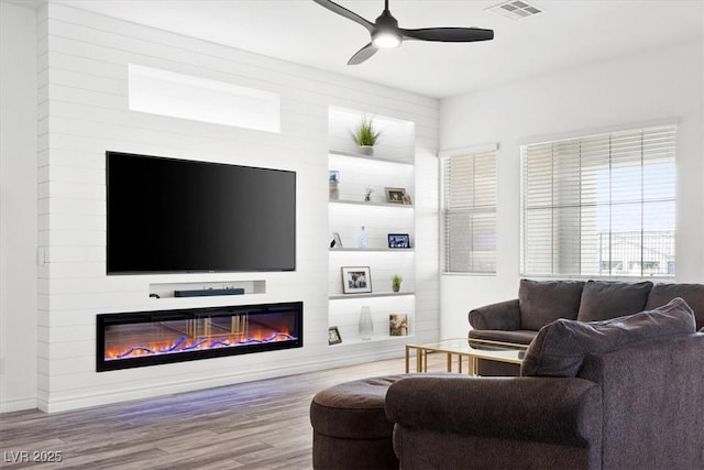 living room featuring hardwood / wood-style flooring, ceiling fan, and a fireplace