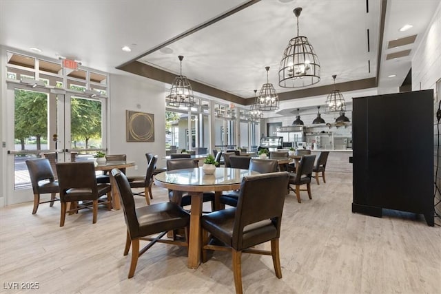 dining room with a raised ceiling, light hardwood / wood-style flooring, and french doors