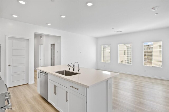 kitchen featuring sink, a center island with sink, light wood-type flooring, dishwasher, and white cabinets