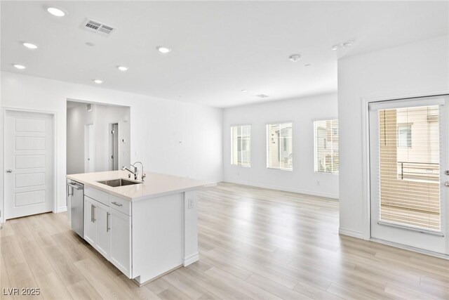 kitchen featuring sink, white cabinetry, a center island with sink, light hardwood / wood-style flooring, and stainless steel dishwasher