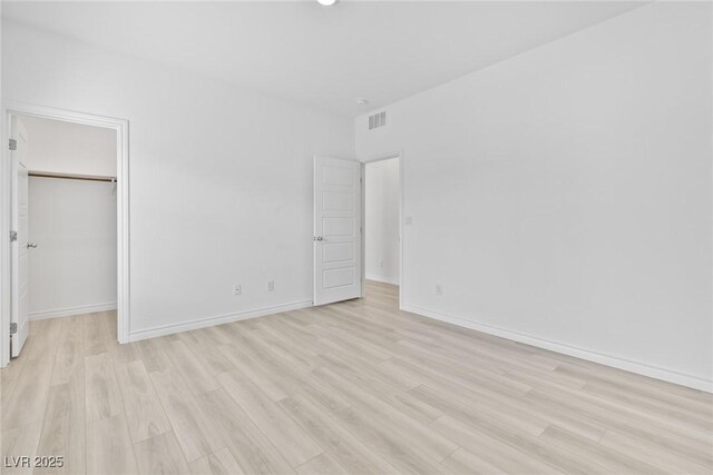 unfurnished bedroom featuring a spacious closet, light wood-type flooring, and a closet